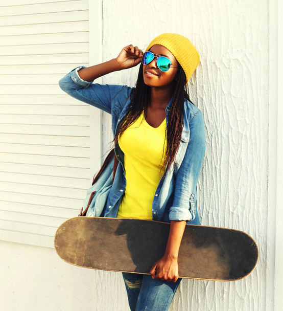 Fashion young african woman with skateboard in colorful clothes  - Foto, imagen