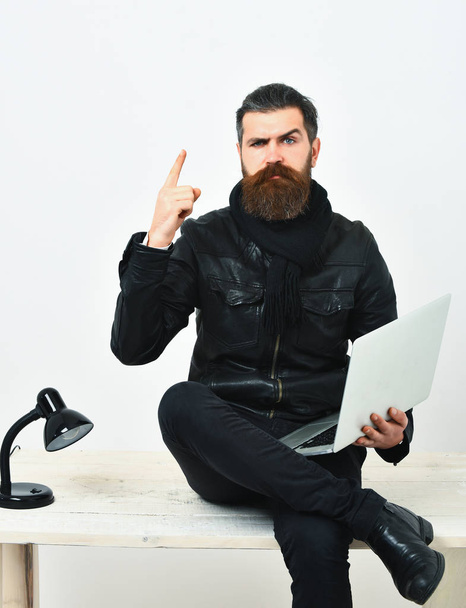 Bearded brutal caucasian hipster sitting on table with laptop - Foto, Imagen