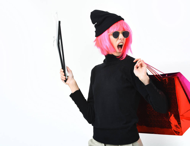 fashionable sexy girl in pink wig holding package with hangers - Zdjęcie, obraz