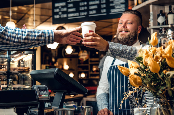 Bearded barista selling coffee to a consumer - Photo, Image