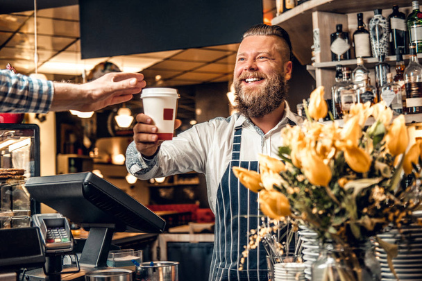 Barista barbudo vendiendo café a un consumidor
 - Foto, Imagen