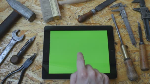 Mano maschile di artigiano artigiano utilizzando tablet pc con schermo verde in officina. Vista dall'alto. Diversi strumenti vintage si trovano accanto
 - Filmati, video