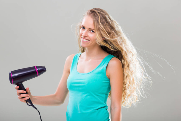 Young woman using hair dryer - Fotografie, Obrázek
