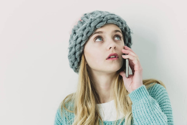 Όμορφη νεαρή κοπέλα σε πουλόβερ, καπέλο με κινητό τηλέφωνο - Φωτογραφία, εικόνα