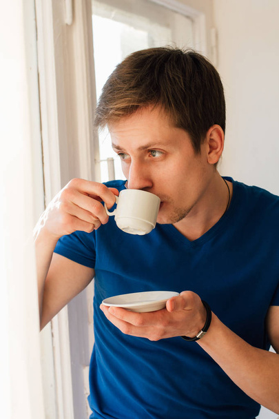 Man drinking coffee looking out the window - Photo, Image