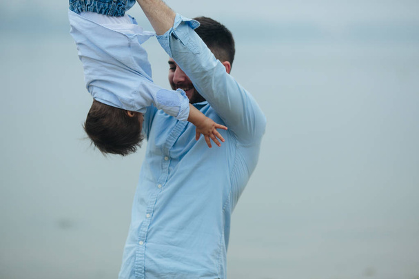 Dad holding infant son by his feet - 写真・画像