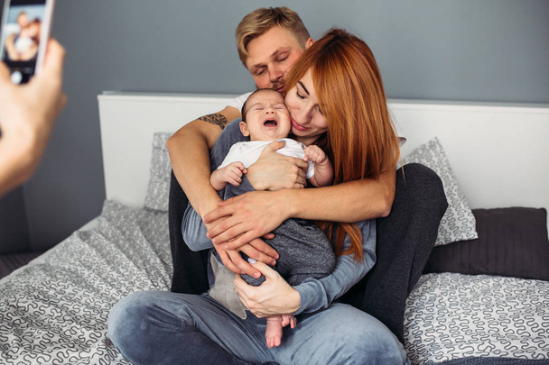 Gelukkige familie met pasgeboren baby op het bed - Foto, afbeelding