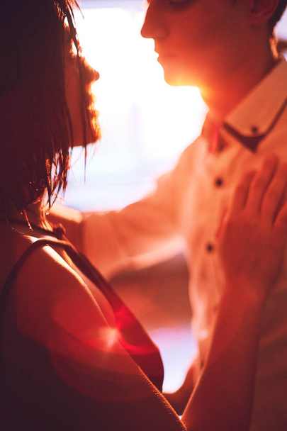 Young people hugging in the apartment in the evening in the rays of the sunset - 写真・画像