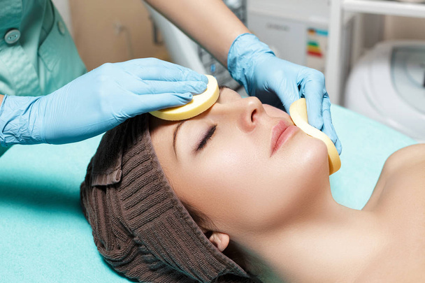 doctor beautician cleanses skin woman with sponge. cosmetology treatment skincare face. Spa procedures - Fotó, kép