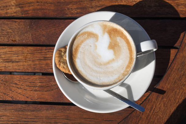 Šálek kávy s cappuccino a mléko pěnou na dřevěný stůl venku v létě, pohled shora - Fotografie, Obrázek