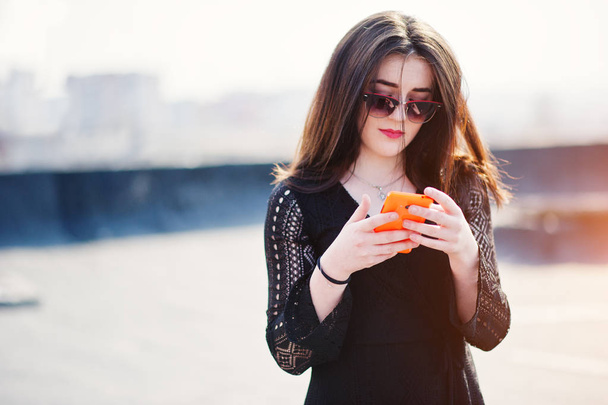 Portrait brunette girl with red lips and orange mobile phone at  - Foto, Bild