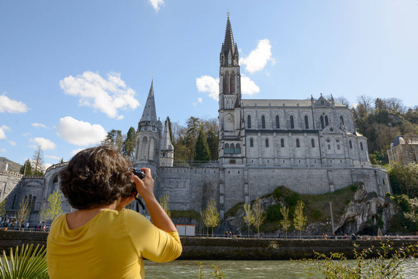 mulher fotografa a catedral de Lourdes, França
 - Foto, Imagem