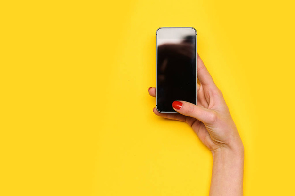 girl touch mobile phone screen with hand on yellow background - 写真・画像