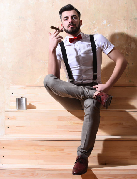 γενειοφόρος άνδρας κάθεται σε ξύλινες σκάλες με σοβαρό πρόσωπο - Φωτογραφία, εικόνα