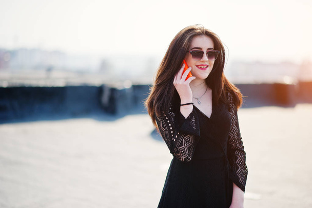 Portrait brunette girl with red lips and orange mobile phone at  - Foto, afbeelding