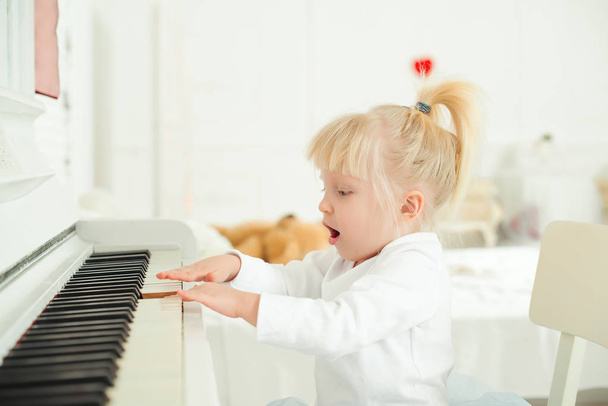 Söpö lapsi tyttö soittaa pianoa studiossa
. - Valokuva, kuva