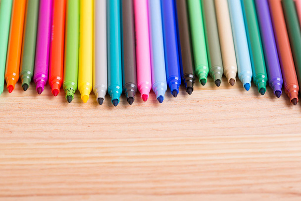 Ahşap bir masanın üzerindeki renkli kalemler. - Fotoğraf, Görsel