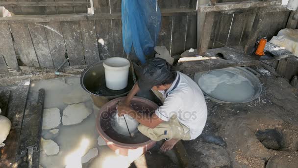 Homme ramollissant les nouilles de riz avec de l'eau dans un seau troué avant de les enlever
 - Séquence, vidéo