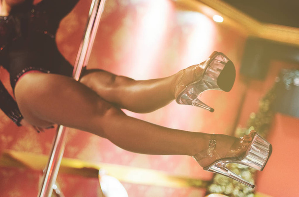 Сексуальная женщина, исполняющая стриптиз на шесте в ночном клубе
. - Фото, изображение