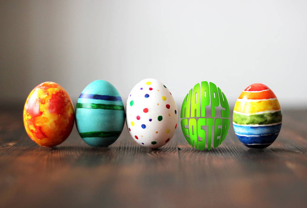 Kleurrijke Pasen eieren op houten achtergrond met ei-vormige woorden Happy Easter. - Foto, afbeelding