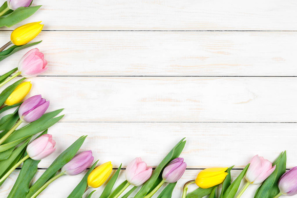 Ramo de tulipanes rosados y amarillos sobre un fondo de madera blanca
 - Foto, Imagen
