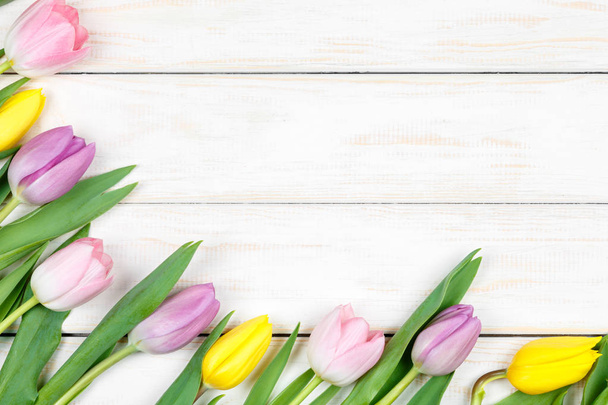 Bunch of pink and yellow tulips lying on a white wooden background - Foto, Imagem