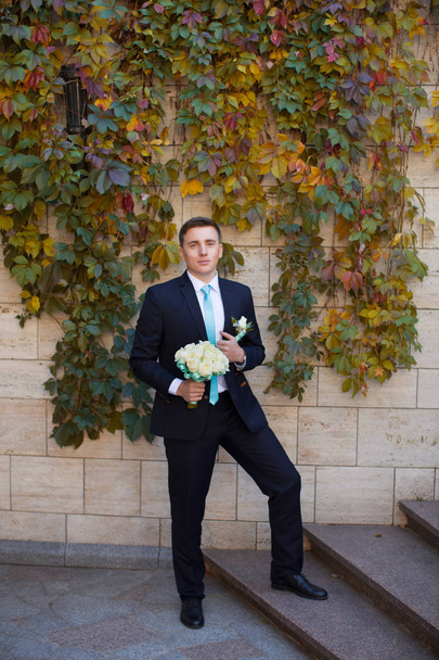 Groom in a stylish suit against a brick wall background - Foto, imagen