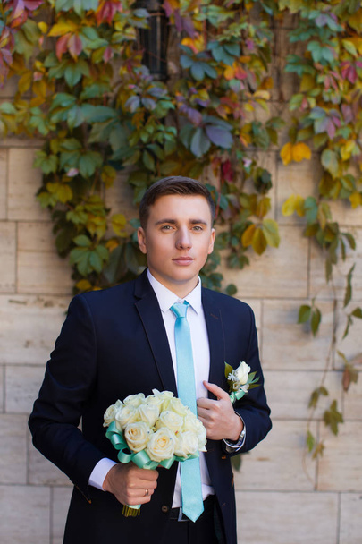 Groom in a stylish suit against a brick wall background - Foto, immagini