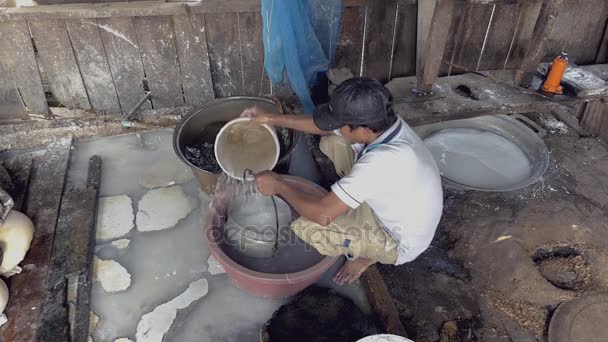 Hombre suavizando fideos de arroz con agua en un cubo hueco antes de quitárselo
 - Imágenes, Vídeo