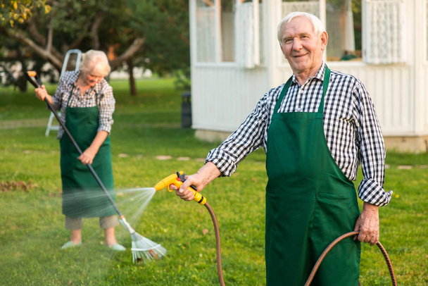 Man with garden hose smiling. - Foto, afbeelding