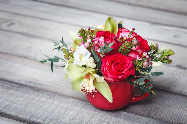 Small red vase with bouquet of flowers and Lilies on wooden table space for text - Foto, Bild