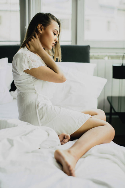 jonge vrouw zit op een bed  - Foto, afbeelding