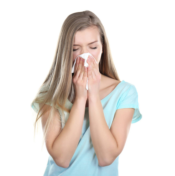 Young woman blowing nose on tissue against white background - Photo, image