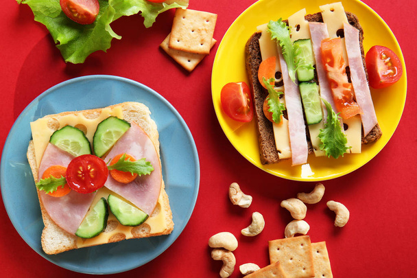 Plates with creative sandwiches on red background - Foto, imagen