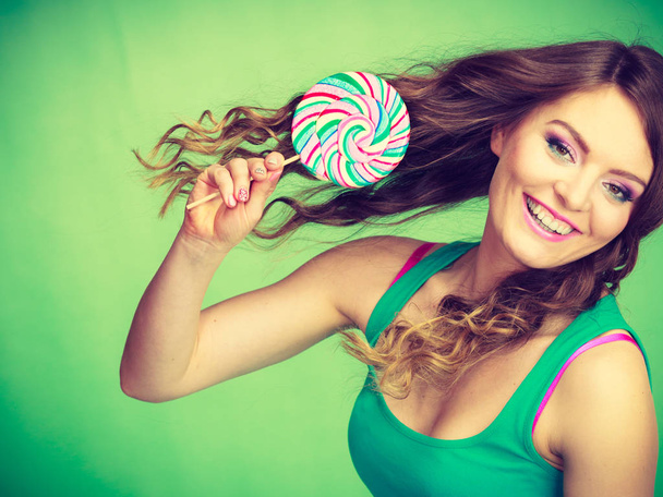Smiling girl with lollipop candy on green  - Zdjęcie, obraz