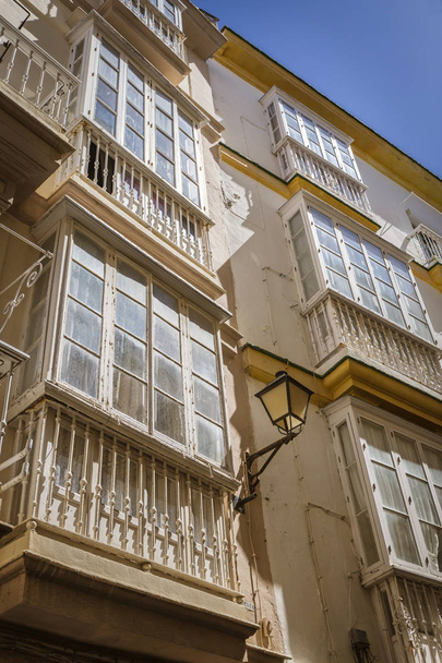 Cadiz Spain- 31 марта: Деталь балконов и больших окон на время девятнадцатого века, Узкая улица с традиционной архитектурой в Кадисе, Андалусия, Южная Испания
 - Фото, изображение