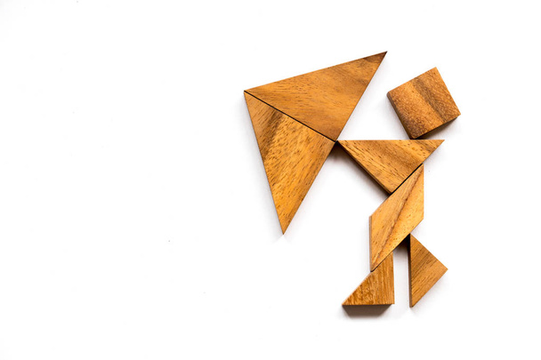 Drewniany tangram jako człowiek trzymać parasol kształt na białym tle (koncepcja jako firma ma kryzys) - Zdjęcie, obraz