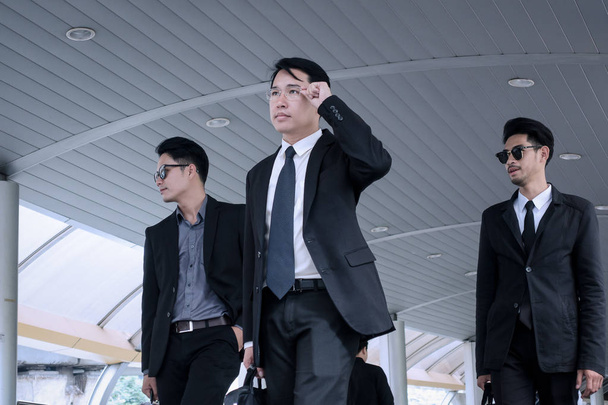 Азиатский бизнесмен с группой телохранителей гуляет по бизнесу
 - Фото, изображение