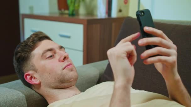 Man Laying on the Sofa and Using Mobile Phone - Filmati, video