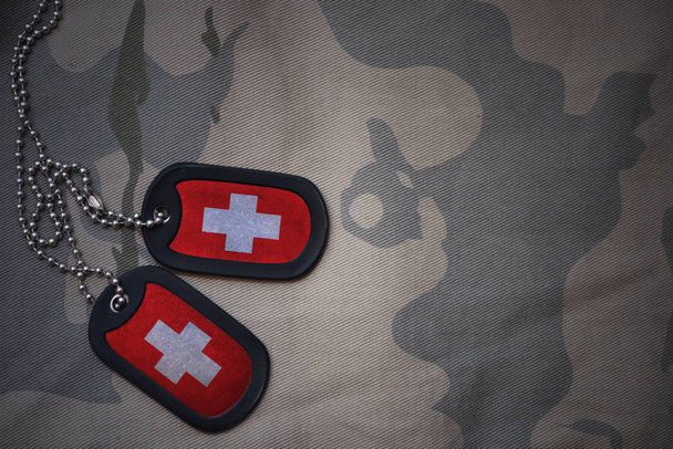 Armee leer, Hundeanhänger mit Schweizer Flagge auf khakifarbenem Hintergrund. Militärisches Konzept - Foto, Bild