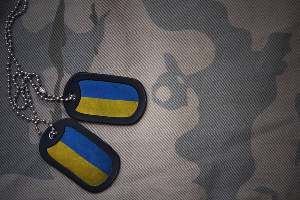 army blank, dog tag with flag of ukraine on the khaki texture background. military concept - Foto, Imagem