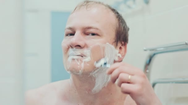 a man shaves in the bathroom. Slow motion - Footage, Video