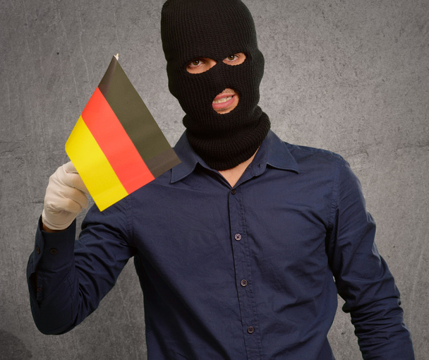 Человек в маске грабителя и с флагом в руках
 - Фото, изображение