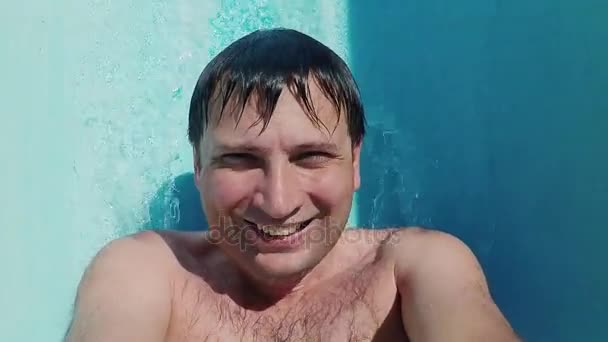 Homem caucasiano descansando em aquapark, puxando para baixo da corrediça de água, olhando para a câmera
 - Filmagem, Vídeo