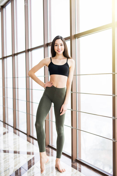 Morena sexy chica de fitness en ropa deportiva con el cuerpo perfecto en el gimnasio posando antes del conjunto de entrenamiento
 - Foto, imagen