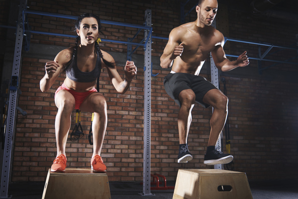 sporty couple jumping on platforms at gym - Photo, Image