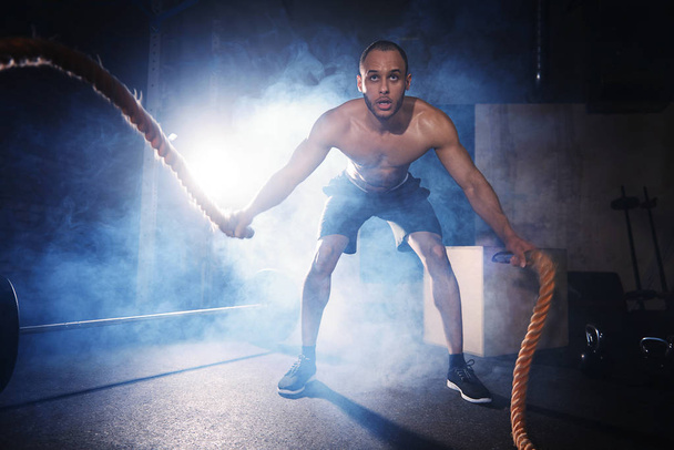 shirtless sportieve man uitoefenend met touwen - Foto, afbeelding