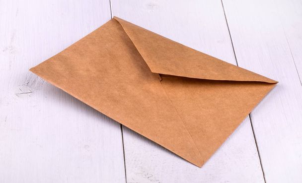 Papieren envelop op een witte houten tafel. - Foto, afbeelding