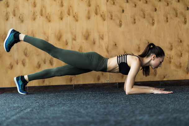 Pleine longueur vue latérale de la jeune belle femme en vêtements de sport faisant planche à la salle de gym
 - Photo, image