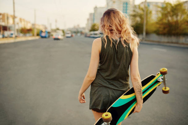 Beautiful young tattooed girl with longboard in sunny weather - Photo, Image